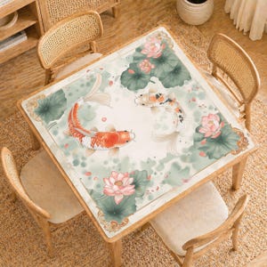 May include: Square wooden table with a decorative top featuring koi carp, lotus flowers, and lily pads in shades of orange, white, and green. The table is surrounded by four wooden chairs with woven backs.