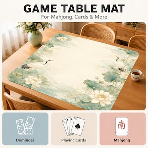 May include: A rectangular game table mat featuring a printed design of white cranes and lotus flowers in shades of green and cream. The mat is displayed on a wooden table and includes text that reads GAME TABLE MAT For Mahjong, Cards & More.