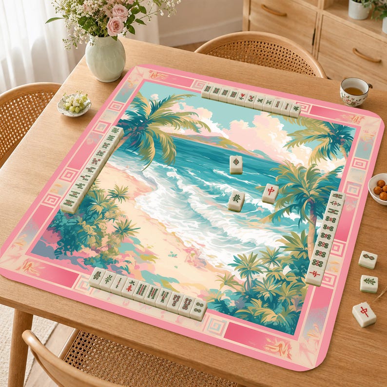 May include: A square mahjong mat featuring a tropical beach scene with palm trees, turquoise ocean waves, and a sandy shore. The mat has a wide pink border with geometric patterns and is set with several white mahjong tiles in rows.