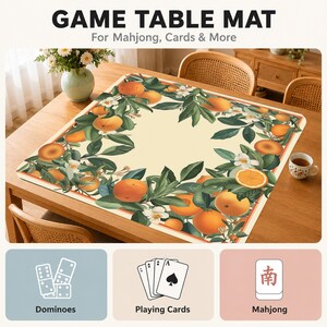 Może przedstawiać: Kwadratowa mata do gier z kremowym środkiem i obramowaniem ozdobionym pomarańczami, zielonymi liśćmi i białymi kwiatami. Tekst brzmi GAME TABLE MAT For Mahjong, Cards & More, z ikonami domina, kart do gry i płytek mahjong.