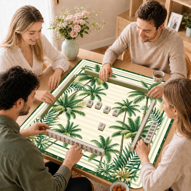 K&ouml;nnte beinhalten: Eine quadratische Mahjong-Matte mit cremewei&szlig; gestreiftem Hintergrund und einem Muster aus gr&uuml;nen Palmenbl&auml;ttern. Die Matte enth&auml;lt mehrere Mahjong-Spielsteine mit chinesischen Schriftzeichen auf der Oberfl&auml;che, umrahmt von einem gr&uuml;nen Rand.