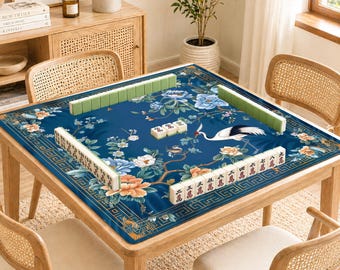 May include: A wooden square table with a blue floral patterned mat, set for a game of Mahjong. The mat features a crane, flowers, and Chinese characters. The table is surrounded by four rattan chairs.