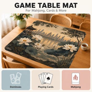 May include: A rectangular game table mat featuring a printed landscape of white lotus flowers, dark green lily pads, and a distant city skyline. The text GAME TABLE MAT For Mahjong, Cards & More is at the top, with icons for dominoes, cards, and mahjong below.