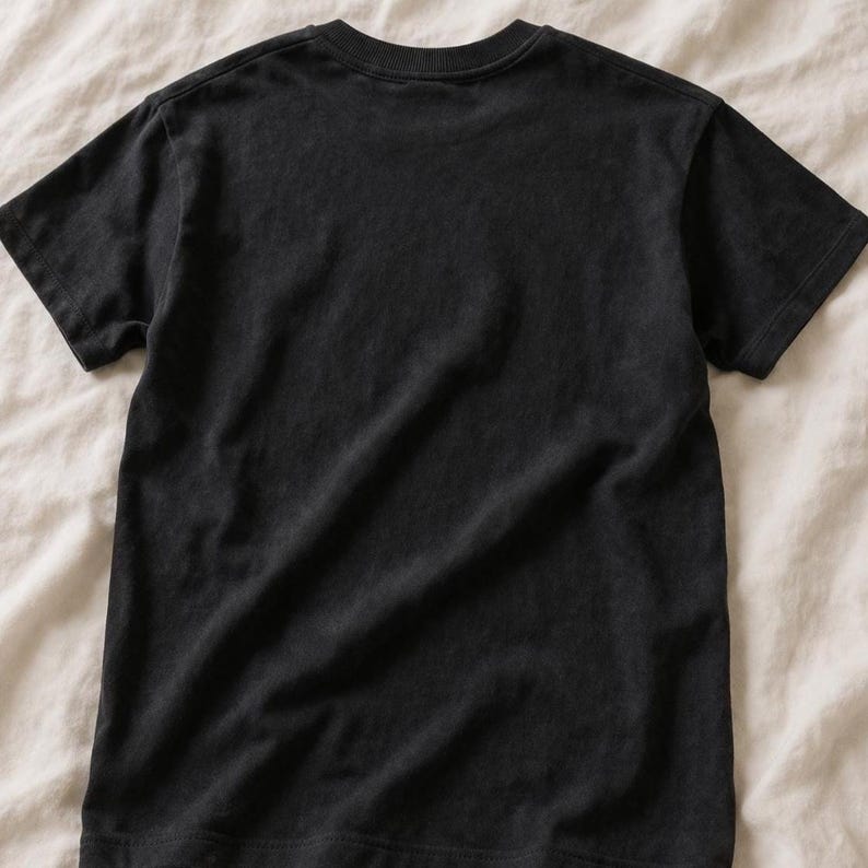 May include: A solid black short-sleeved t-shirt featuring a classic crew neckline. The garment is displayed flat, showcasing the plain back side of the shirt with visible stitching along the sleeves, hemline, and collar, maintaining a simple design.