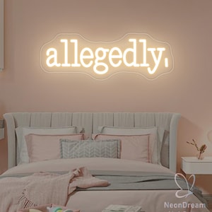 May include: A neon sign in a bedroom reads "allegedly," in a cursive font. The sign is white and mounted on a pink wall above a bed with pink bedding. The room has a soft, feminine aesthetic.