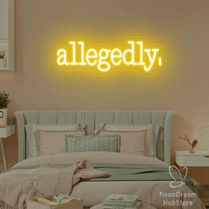 May include: A neon sign in a bedroom spells out the word "allegedly" in a bright yellow color. The sign is mounted on a peach-colored wall above a bed with pink and gray bedding. The room has a modern, minimalist aesthetic.