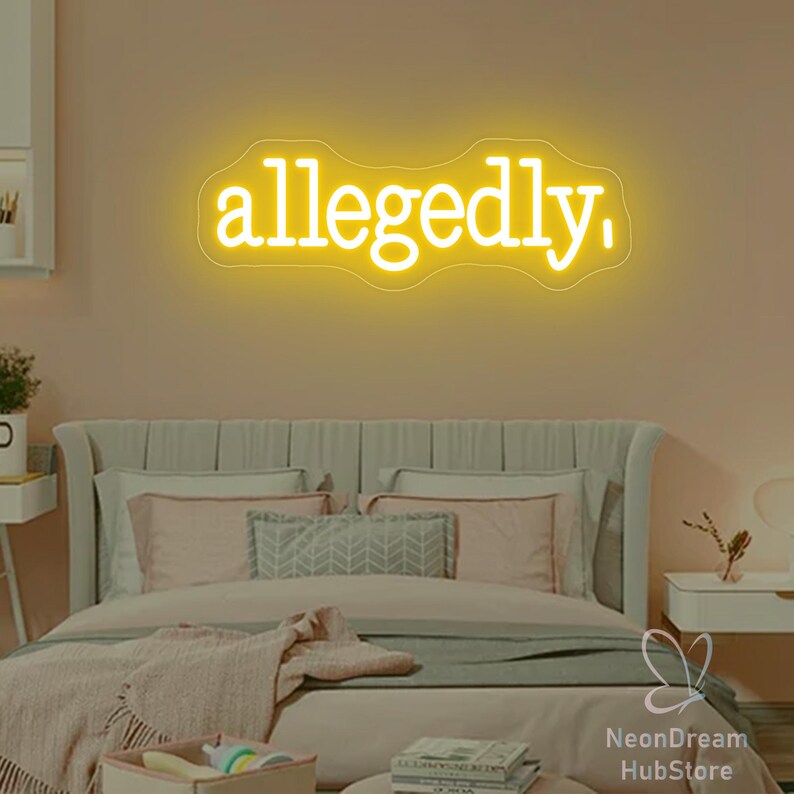 May include: A neon sign in a bedroom spells out the word "allegedly" in a bright yellow color. The sign is mounted on a peach-colored wall above a bed with pink and gray bedding. The room has a modern, minimalist aesthetic.
