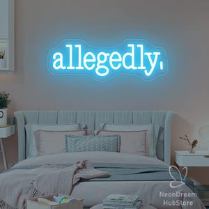May include: A blue neon sign displaying the word "allegedly," in a cursive font. The sign is mounted on a wall above a bed with pillows and blankets. The room has a soft, pinkish hue.