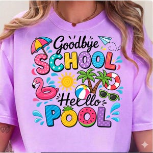 May include: A light purple t-shirt with the words "Goodbye School Hello Pool" in colorful, playful lettering. The design includes a flamingo, sun, palm trees, and other summer-themed graphics.