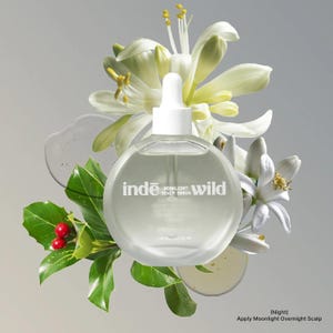 Op de afbeelding: Een heldere, ronde fles Inde Wild Moonlight Scalp Serum met een witte druppelaar, omringd door witte bloemen, groene bladeren en rode bessen. De fles heeft witte tekst met de tekst "Inde Moonlight Scalp Serum Wild".