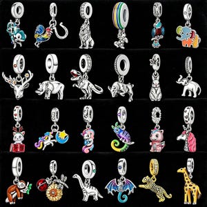May include: A collection of silver-toned charm pendants featuring various animal and fantasy designs. The charms include a lion, elephant, dinosaur, unicorn, and more, with colorful enamel accents. Each charm has a loop for attaching to a bracelet or necklace.