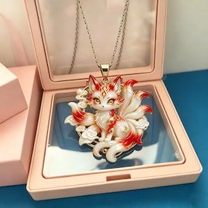 May include: A pendant necklace featuring a multi-tailed fox with white and red fur, gold accents, and yellow eyes. The fox is positioned within a circular frame decorated with cloud motifs. The pendant hangs from a thin silver-toned metal chain.
