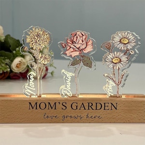 Può includere: Una tazza di ceramica bianca con manico nero e la scritta "But First, Coffee" in grassetto nero. La tazza è appoggiata su una superficie di legno. La tazza è alta circa 10 cm.