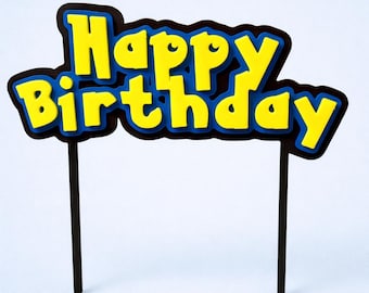 May include: A yellow and blue "Happy Birthday" cake topper with a black border and two black sticks. The text is in a bold, playful font, perfect for a birthday celebration.