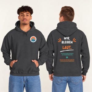 May include: A dark gray hooded sweatshirt featuring a circular logo with a raised fist on the front. The back displays the text WIR BLEIBEN LAUT, F&uuml;r eine starke Zukunft der Heilmittelberufe, and B&uuml;ndnis Zukunft Therapieberufe with a heart icon.
