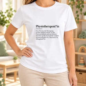 May include: A white short-sleeved t-shirt featuring black text that reads: Physiotherapeut*in [Substantiv] Eine Person, die Bewegung wieder möglich macht, an das Potenzial glaubt und aus kleinen Schritten große Fortschritte zaubert. Schmerzdetektiv*in, Motivator*in, Alltagsheld*in.