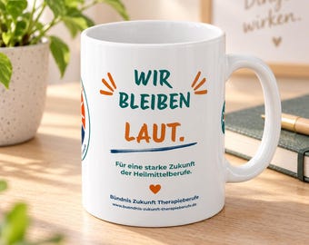 May include: A white ceramic mug featuring the text WIR BLEIBEN LAUT. in teal and orange, with the subtext Für eine starke Zukunft der Heilmittelberufe, a small orange heart, and the website Bündnis Zukunft Therapieberufe printed on the front.