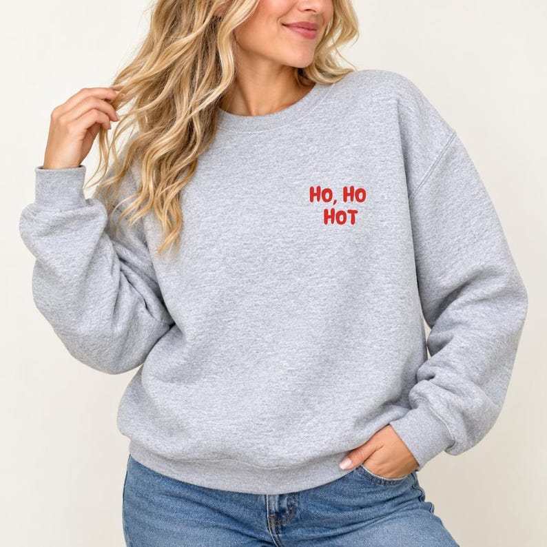 Frau trägt graues Sweatshirt mit rotem Brustaufdruck Ho, Ho Hot, lustiger Weihnachtspulli