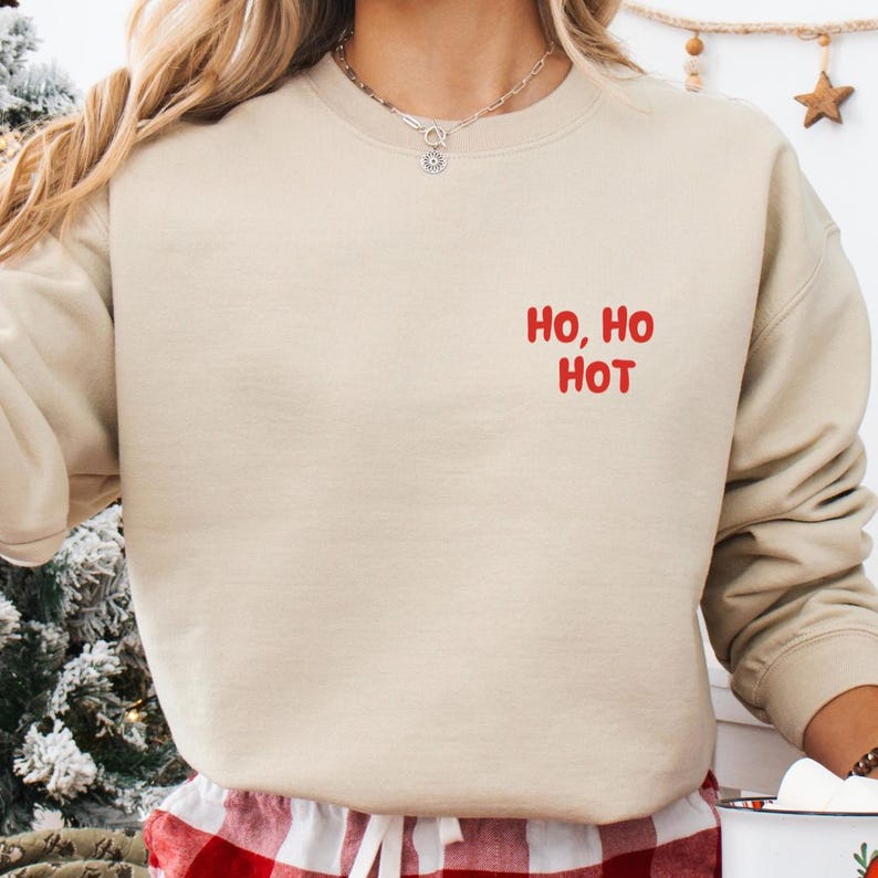Frau trägt beiges Weihnachtssweatshirt mit rotem Schriftzug Ho, Ho Hot auf der Brust