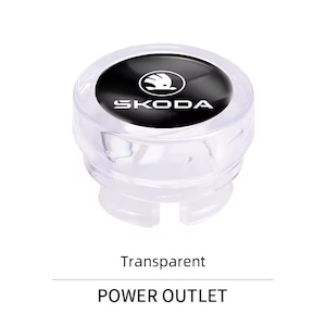 May include: A transparent power outlet cover with the Skoda logo in black and white. The text "POWER OUTLET" is below the cover. The cover is made of clear plastic.