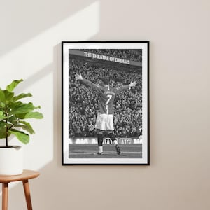 Könnte beinhalten: Schwarz-Weiß-Druck in einem Rahmen, der einen Fußballspieler in einem roten Trikot mit der Nummer 7 und dem Namen Ronaldo zeigt, der mit ausgestreckten Armen jubelt. Das Stadion-Schild lautet "THE THEATRE OF DREAMS".