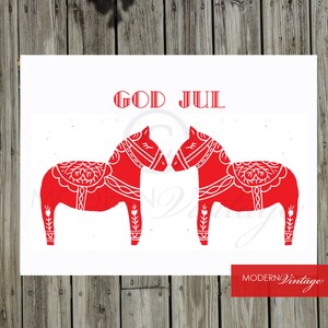 May include: A white card with the text "God Jul" in red lettering. Two red stylized horses face each other. The horses are traditional Swedish Dala horses.