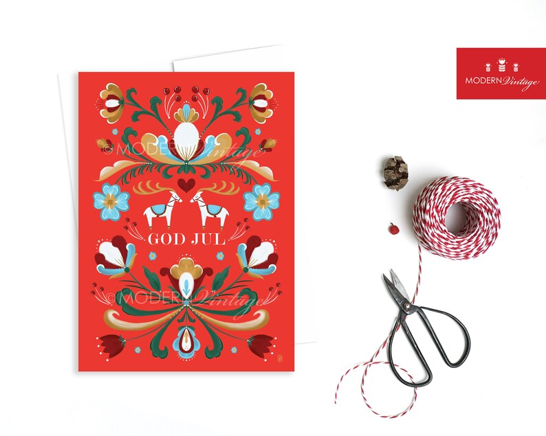 May include: Red Christmas card with a Scandinavian folk art design featuring two white horses, stylized flowers, and the text "God Jul" in gold lettering.