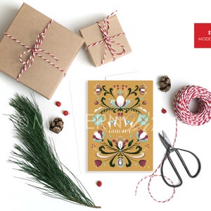 May include: A yellow Christmas card with a Scandinavian folk art design featuring a floral pattern, two reindeer, and the text "God Jul".