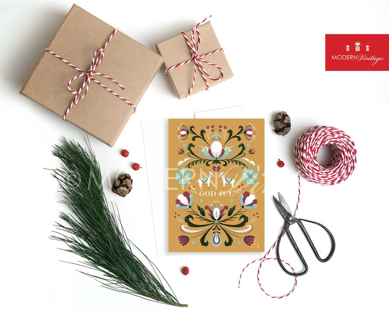 May include: A yellow Christmas card with a Scandinavian folk art design featuring a floral pattern, two reindeer, and the text "God Jul".