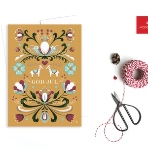 May include: A yellow Christmas card with a Scandinavian folk art design featuring stylized flowers, a heart, and two white horses. The text "God Jul" is written in white.