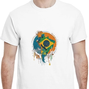 May include: White t-shirt featuring a colorful graphic of the Brazilian flag within a circular design. The design incorporates blue, green, yellow, and orange paint splatters, creating a vibrant and artistic look. The shirt is a classic crew neck style.