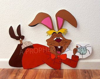 May include: A cartoon illustration of the White Rabbit from Alice in Wonderland. He is lying on his side, wearing a red jacket, a white shirt, and a bow tie. He has a cup of tea in his hand and is smiling.