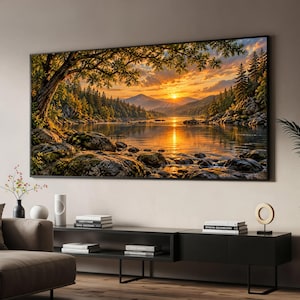 May include: A large rectangular wall art print featuring a landscape scene of a calm lake surrounded by dense pine forests and rocky shores at sunset. The golden sun sits low over distant mountains, casting a warm glow across the water surface.