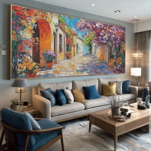 Può includere: Un grande dipinto a olio rettangolare raffigura una vivace scena di strada europea. L'opera presenta un sentiero acciottolato che conduce verso un cielo blu brillante, affiancato da edifici colorati e fiori lussureggianti. Il dipinto è incorniciato in una cornice dorata.
