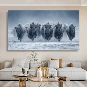 May include: A canvas print featuring a herd of bison running towards the viewer. The bison are dark brown and appear to be kicking up dust or snow. The background is a muted, cool-toned landscape.