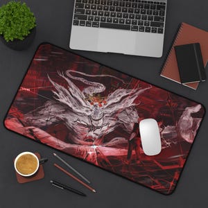 May include: A rectangular desk mat featuring a dark red and black graphic illustration of a monstrous, multi-limbed creature with a white, wispy form and a central glowing emblem, set against a background of abstract geometric lines and sharp red light.
