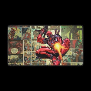 May include: Rectangular desk mat featuring a comic book collage with Deadpool in a dynamic pose, holding a gun and firing. The mat has a black border and a vibrant, colorful design.
