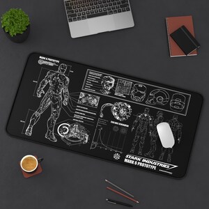 May include: Black rectangular mousepad featuring a white schematic design of the Iron Man Mark 6 Prototype. The design includes diagrams, blueprints, and the Stark Industries logo. A white computer mouse is on the right.