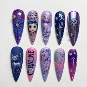 May include: A set of ten long, pointed artificial nails with various designs. The designs include a spiderweb, a character face, a cat, a skeleton hand, a key, and the word "Coraline". Colors include purple, blue, pink, and iridescent.