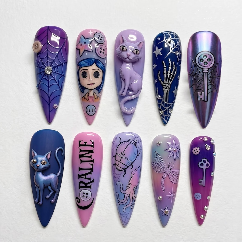 May include: A set of ten long, pointed artificial nails with various designs. The designs include a spiderweb, a character face, a cat, a skeleton hand, a key, and the word "Coraline". Colors include purple, blue, pink, and iridescent.
