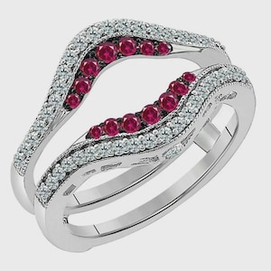 May include: A silver ring guard with a curved design. The ring features a row of small, round, red gemstones and a row of small, clear gemstones. The ring guard is designed to be worn with another ring.
