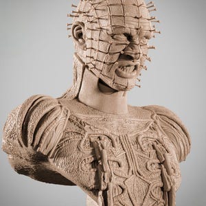 May include: A detailed bust sculpture of a character with a grid-like structure on the face, numerous pins, and intricate chest armor. The sculpture is a monochromatic beige color, with a focus on texture and detail.
