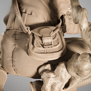 May include: A detailed view of a tan leather satchel with a buckle closure and a shoulder strap. The satchel is attached to a larger, textured, tan fabric structure. The image has a sepia tone.