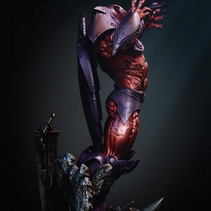 May include: A detailed sculpture of a red-skinned, muscular humanoid figure with purple armor and a helmet. The figure is posed dramatically, with one arm raised and clawed fingers extended. The sculpture is set against a dark background.