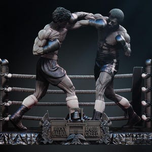 Puede incluir: Estatua detallada que representa un combate de boxeo entre Rocky Balboa y Apollo Creed. Las figuras musculosas llevan guantes y pantalones cortos de boxeo, y están situadas en un ring. La estatua es predominantemente gris con detalles en negro.