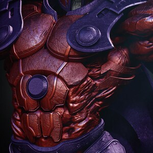 May include: Close-up of a detailed, textured, red and purple armored chest and shoulder piece. The armor has a metallic appearance with rivets and circular accents. The design suggests a fantasy or science fiction theme.