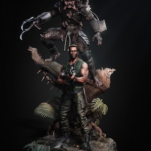 May include: A detailed statue featuring characters from the Predator movie franchise. The statue depicts a muscular man holding a weapon, with a Predator figure looming above. The base includes foliage and the word "PREDATOR" in red.
