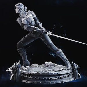 May include: A detailed statue of a woman in a dynamic pose, holding a sword. The figure is dressed in textured clothing and stands on a circular base with skulls and chains. The statue is predominantly gray with dark shadows.