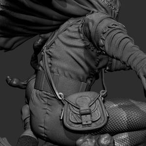 May include: A detailed grayscale sculpture of a fantasy character. The figure wears a hooded cloak, textured clothing, and a small satchel. The design includes intricate stitching and scale-like patterns, suggesting a mythical or medieval theme.