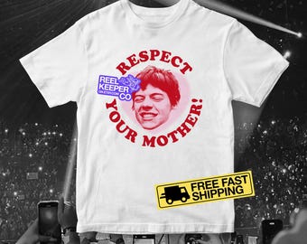 May include: White t-shirt with a graphic featuring a smiling face inside a pink circle, surrounded by the words "Respect Your Mother!" in red. A small logo and a yellow sign are also visible.